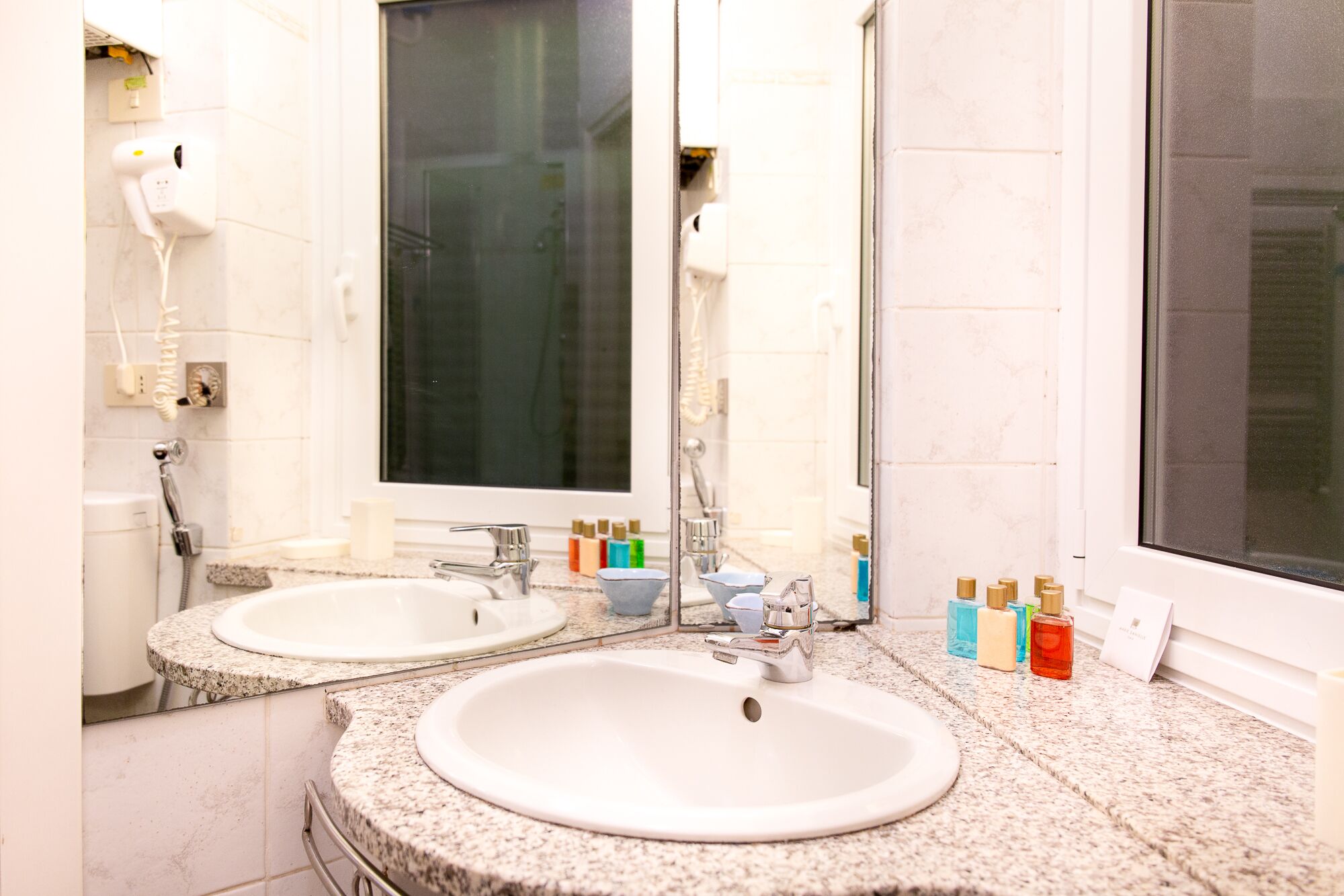 Un baño con dos lavamanos, un espejo y una ventana.