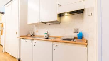 A kitchen with white cabinets, a wooden countertop, a stainless steel sink, and a blue container.