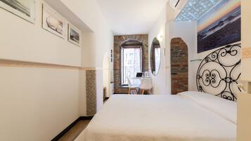Habitación de hotel con cama, escritorio con una computadora portátil, ventana con vistas y un cuadro en la pared.