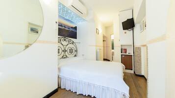 A bedroom with a bed, a wall-mounted TV, a radiator, and a door leading to a bathroom.