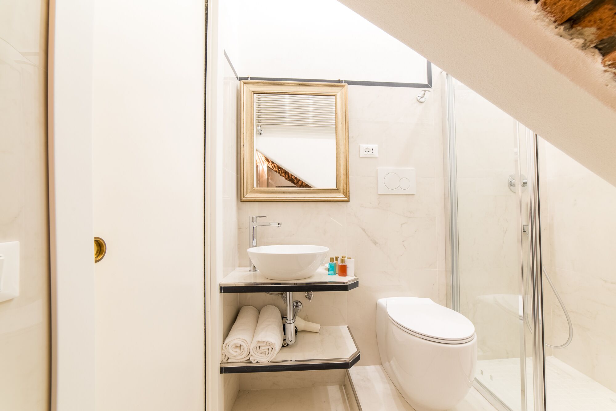 Et moderne badeværelse med en hvid vask, et spejl, et toilet og en brusekabine i glas.