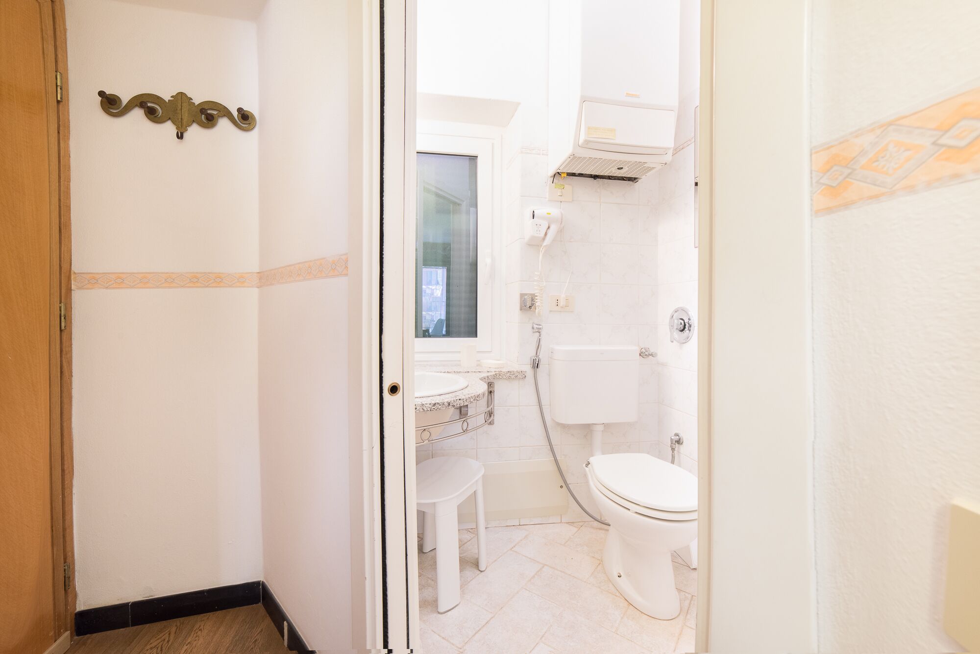 A narrow bathroom with a toilet, a sink, and a shower.