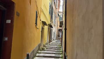 Um beco estreito com uma escadaria que leva a um edifício de paredes amarelas e porta vermelha.