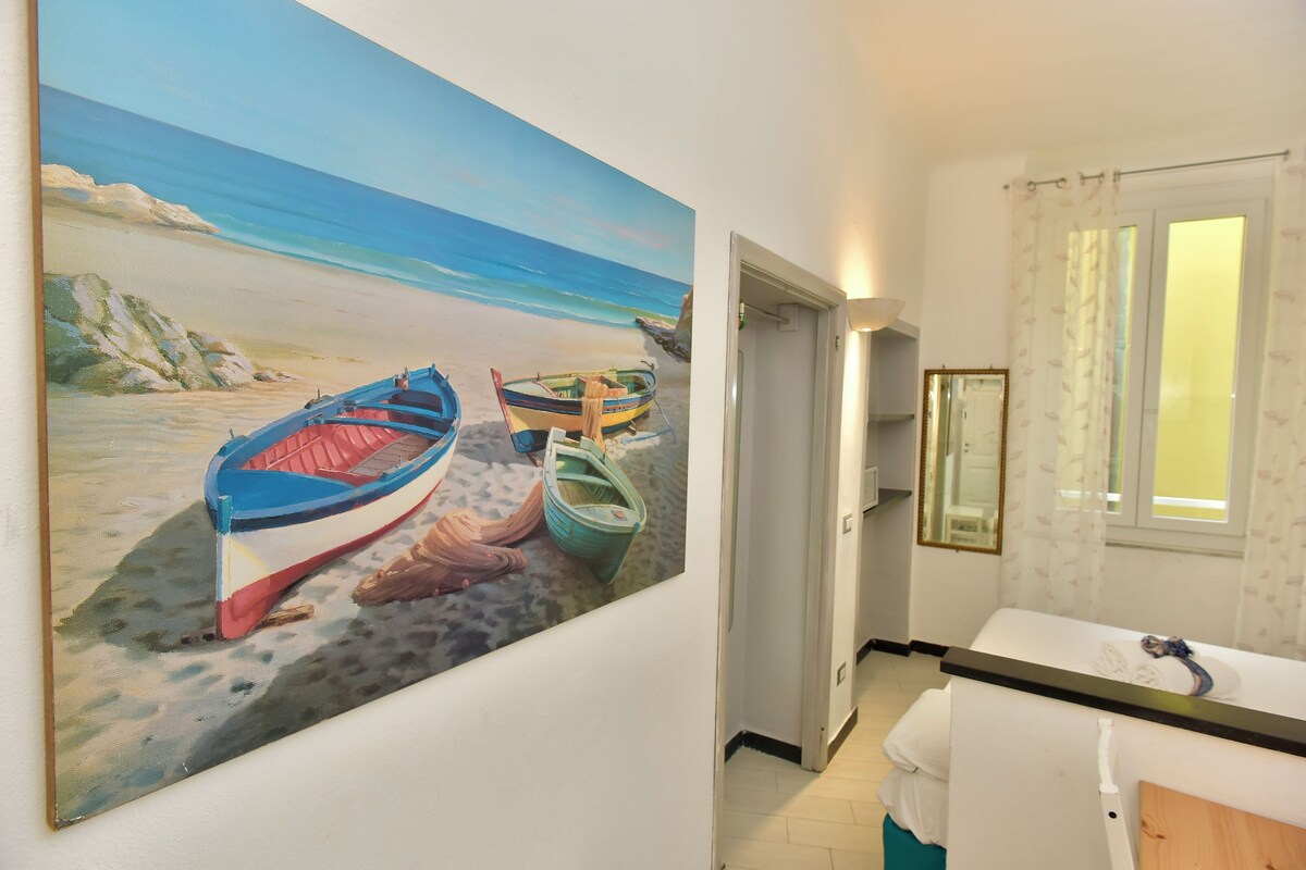A room with a large beach painting, a bathtub, and a window with curtains.