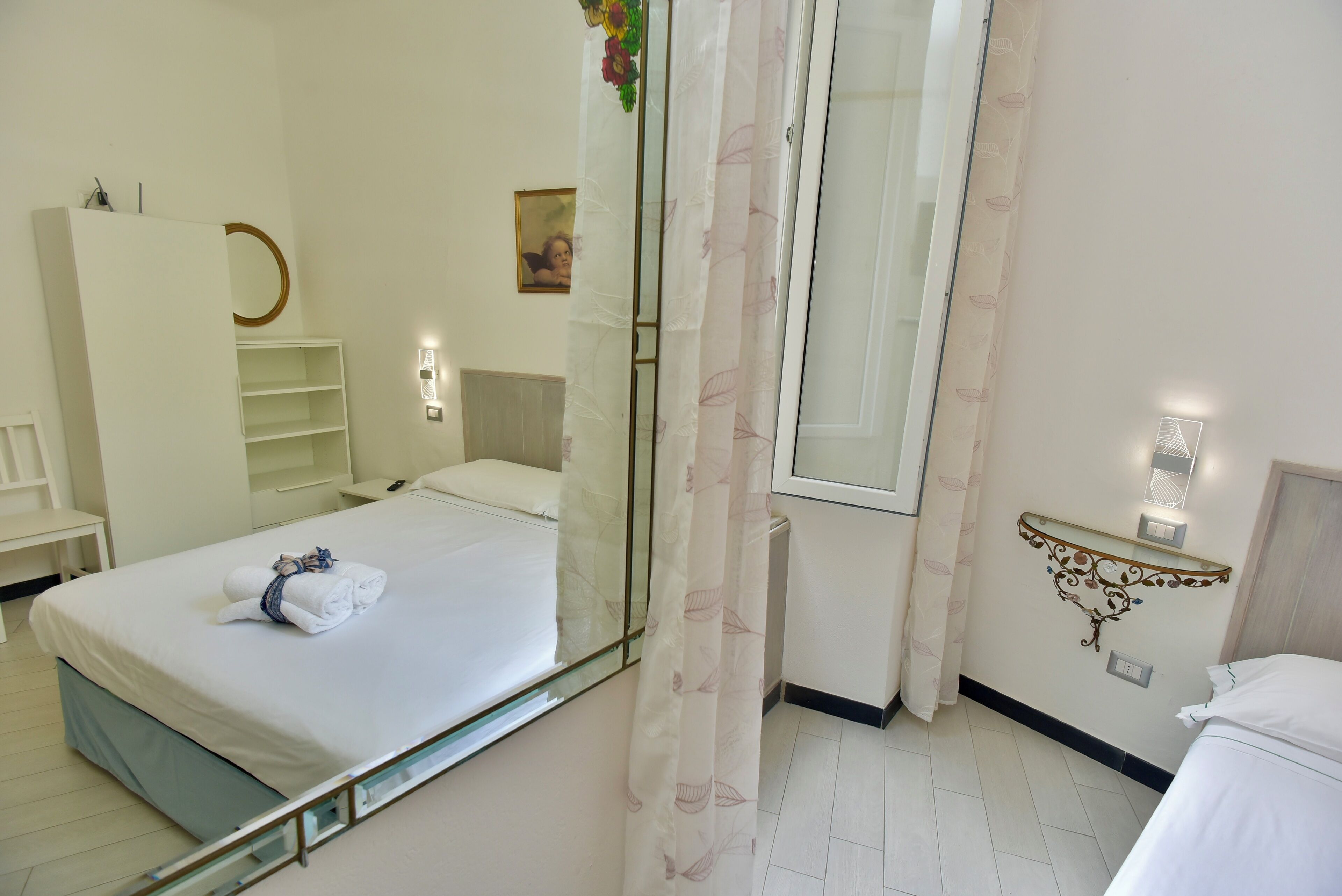 Habitación de hotel con cama, armario, espejo, mesita de noche y estante en la pared.