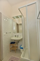 Un baño con ducha, lavamanos y espejo.