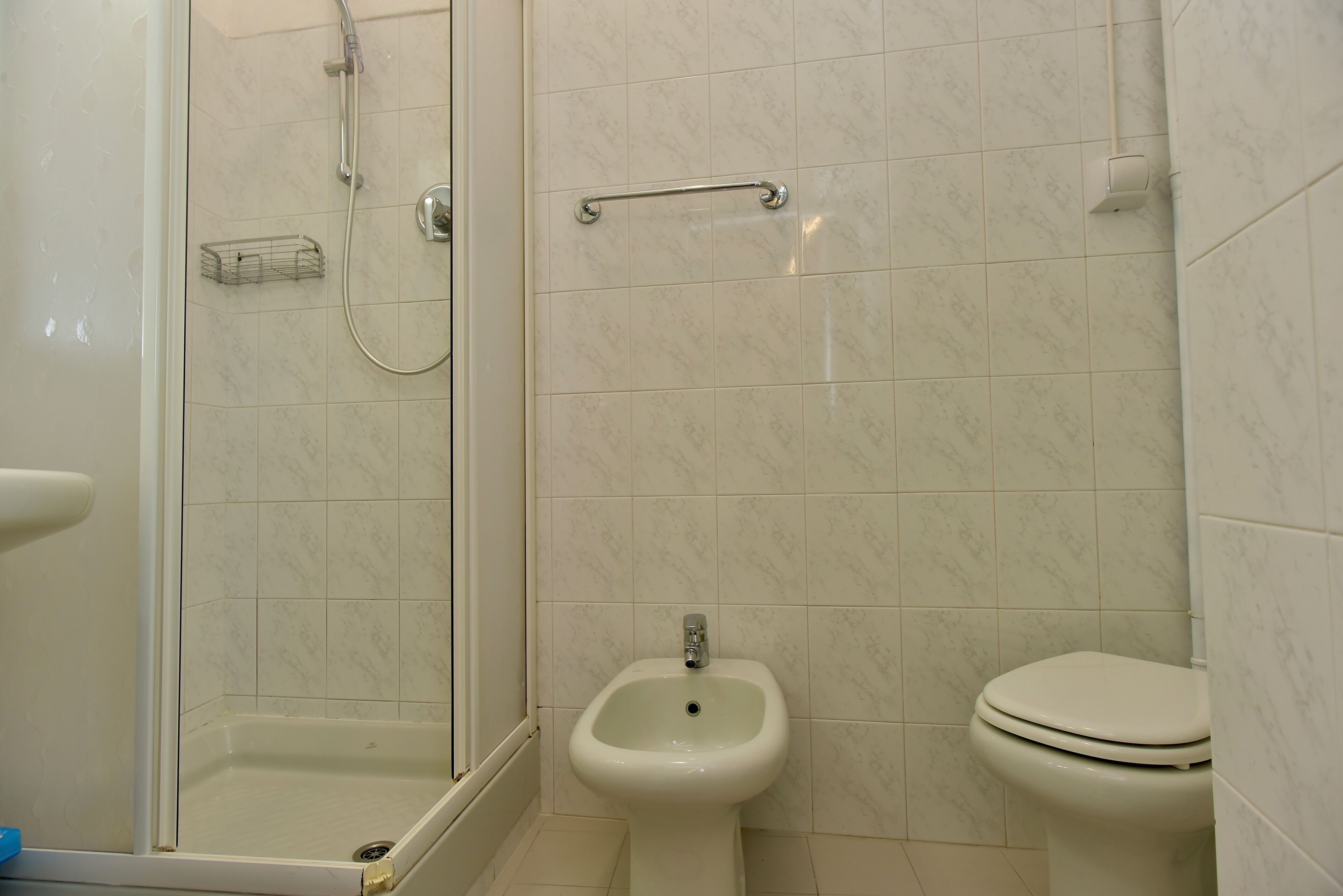 Et badeværelse med bruser, bidet og toilet.