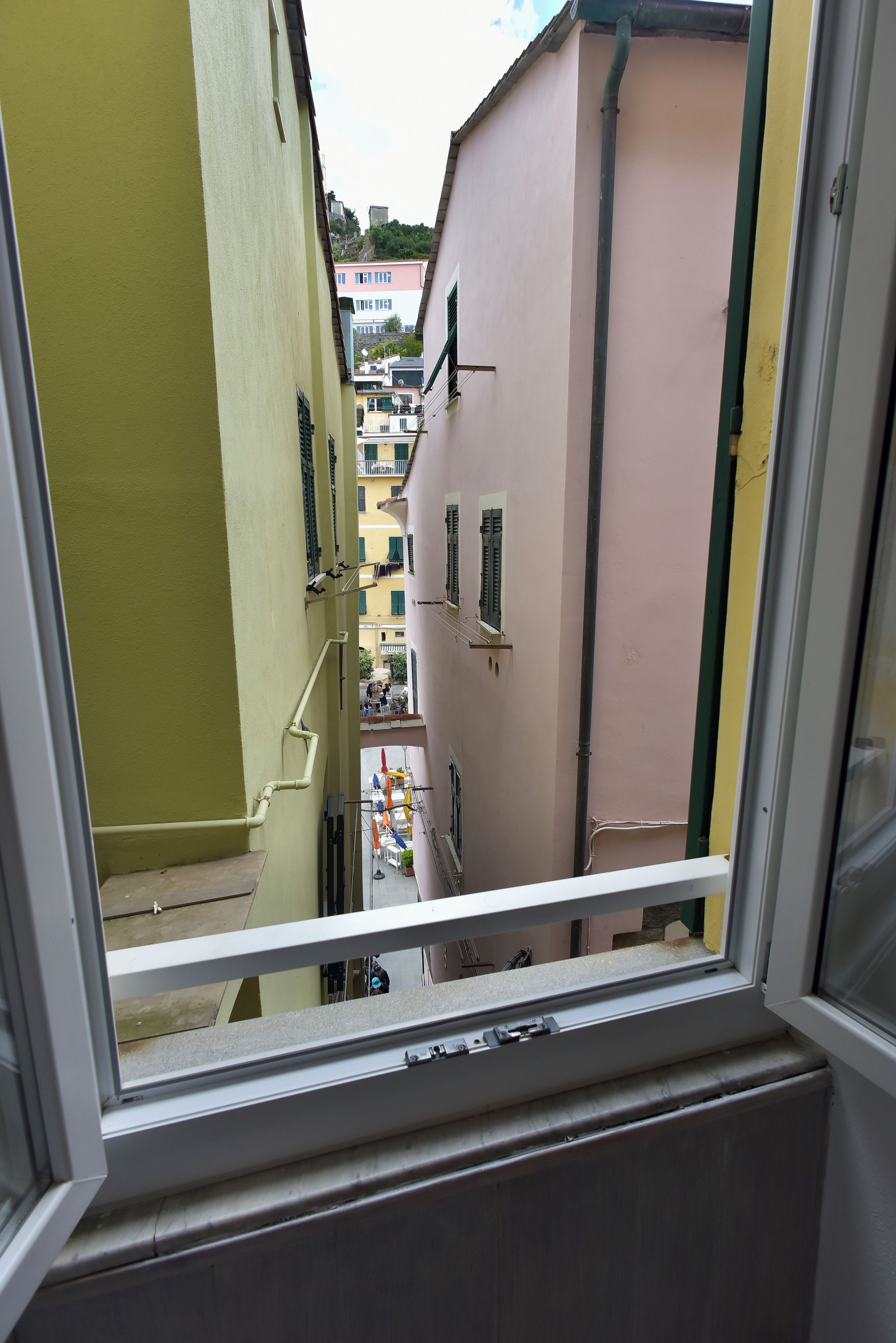 Vista de una calle estrecha a través de una ventana, con edificios a ambos lados.