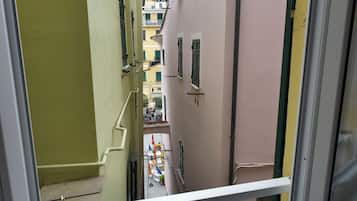 A narrow street view through a window, with buildings on either side.