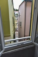 Vista de una calle estrecha a través de una ventana, con edificios a ambos lados.