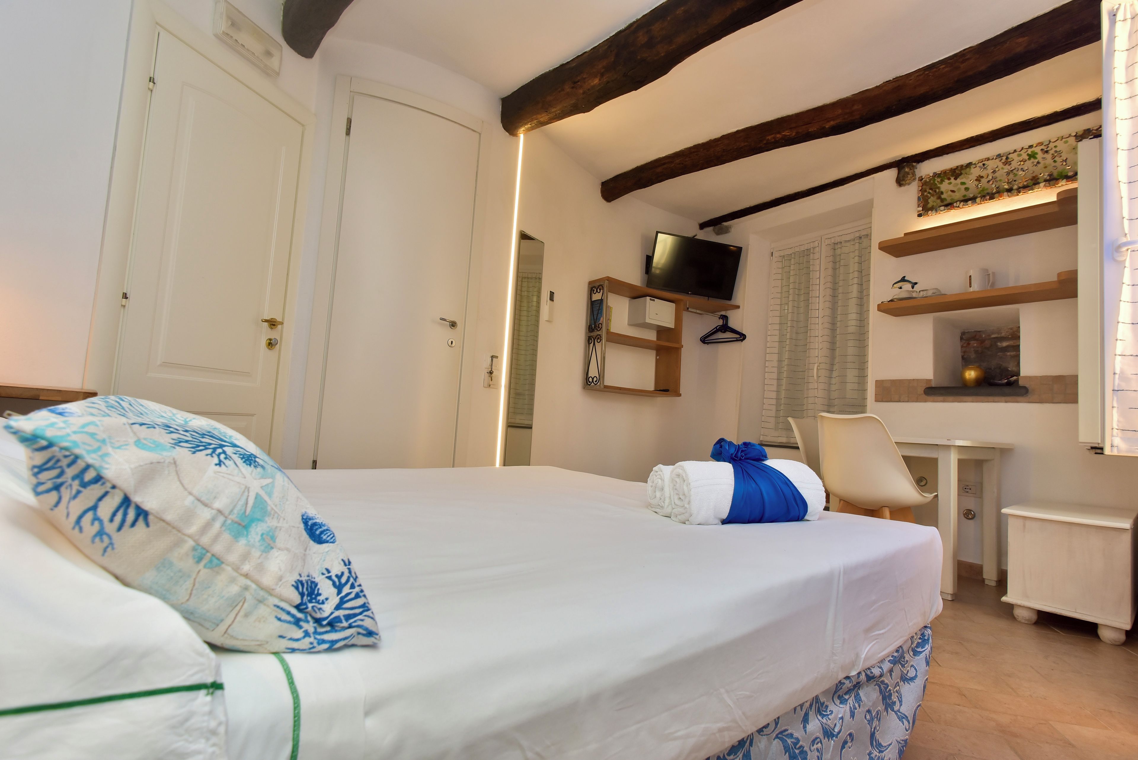 A hotel room with a bed, a desk, a television, and a bathroom.