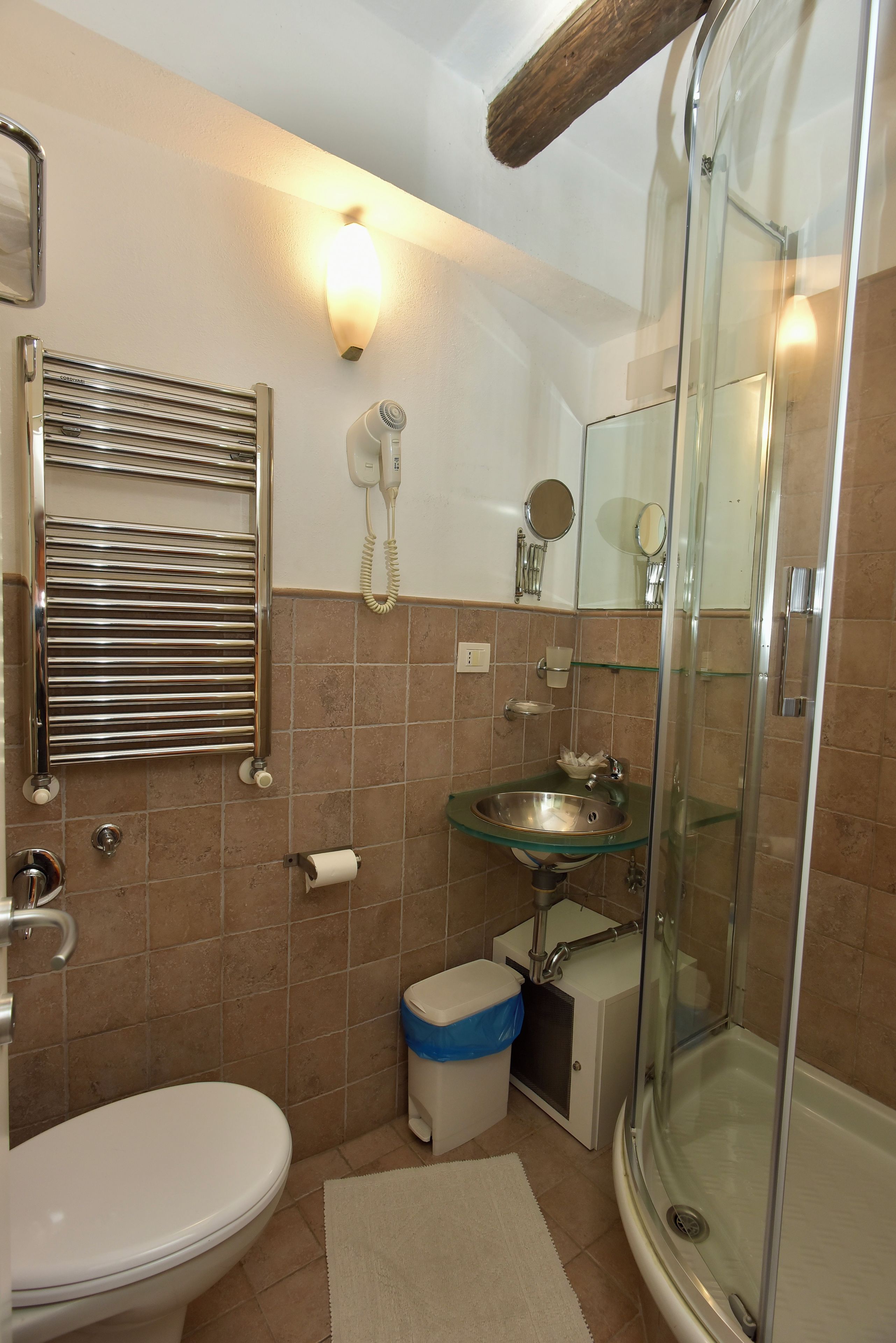 Een badkamer met toilet, wastafel, douche en een handdoekrek.