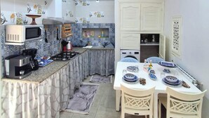Une cuisine compacte comprenant un coin repas, un four à micro-ondes, une cuisinière et un évier.