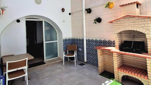 Une terrasse extérieure avec une cheminée en briques, une table à manger avec des chaises et un garde-corps décoratif.
