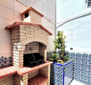 A brick-built outdoor grill with a chimney, set against a tiled wall with blue and white patterns. - MAHDIA BORJ ERRAS (CAP AFRICA) (Mahdia)