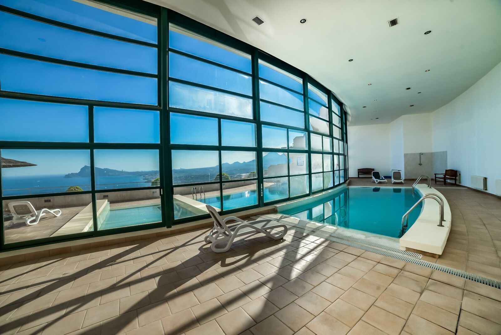 Ein großes Hallenbad mit freiem Blick auf das Meer und die Berge durch große Fenster.