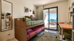 Une chambre à coucher de taille modeste, équipée d’un lit superposé, d’un bureau et d’un balcon avec vue.