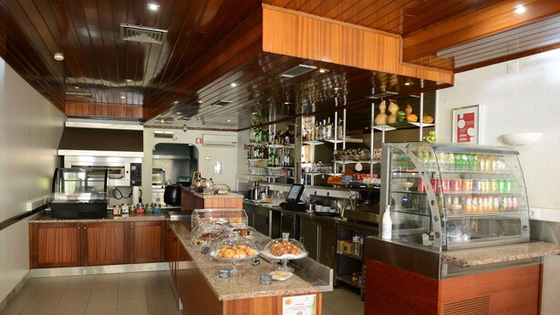 A breakfast bar with a coffee machine, a fruit display, and a refrigerated beverage case. - Estalagem Sequeira (Sao Bras de Alportel)