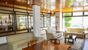 A spacious living area with a wooden dining table, beige sofas, and a glass display of pottery. - Estalagem Sequeira (Sao Bras de Alportel)