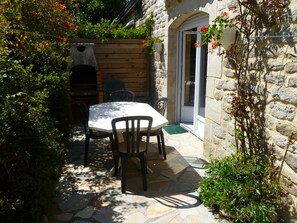 A stone patio with a table and chairs, a stone wall, and a door with a window.