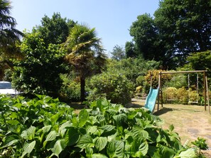 A garden with a swing set and lush greenery.