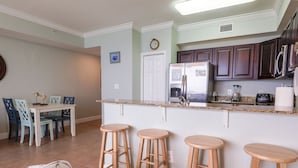 Una cocina moderna con una isla central, taburetes de bar y una zona de comedor con sillas.