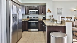 Una cocina moderna con electrodomésticos de acero inoxidable, gabinetes de madera oscura y encimera de granito.
