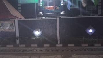 Een gebouw met een verlichte entree en een overdekte ruimte waar een auto geparkeerd staat.