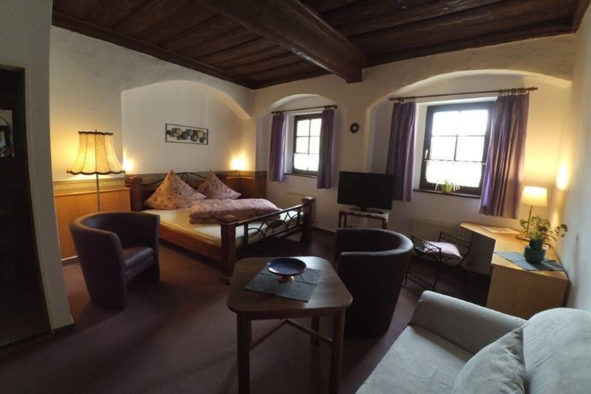 Una habitación acogedora con cama, escritorio, televisor y silla.