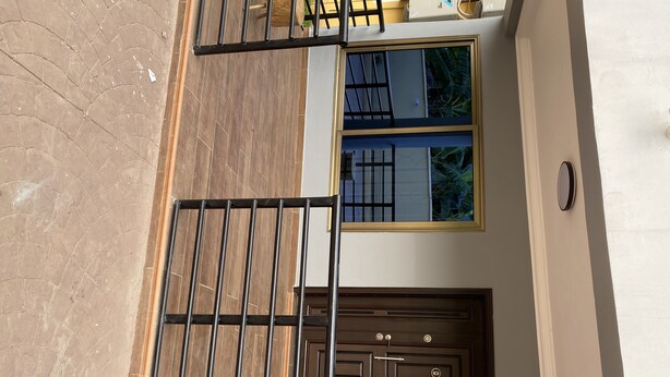 Blick auf die Außenansicht eines Hauses, einschließlich eines verschlossenen Eingangsbereichs, eines Fensters mit Blick auf Grünflächen und einer Tür mit modernem Design.