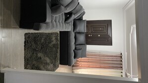 Ein modernes Wohnzimmer mit einer Eckcouch, einem dunklen Holzschrank und einem flauschigen Teppich.