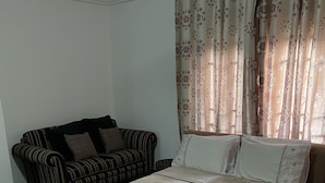 Ein Schlafzimmer mit Bett, einer Couch und Vorhängen.