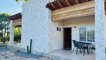 Un edificio de piedra con techo de madera, una puerta numerada con el número 3, y un patio con mesa y sillas.