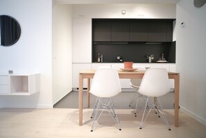 Una cucina moderna con mobili bianchi, un tavolo di legno e due sedie bianche.
