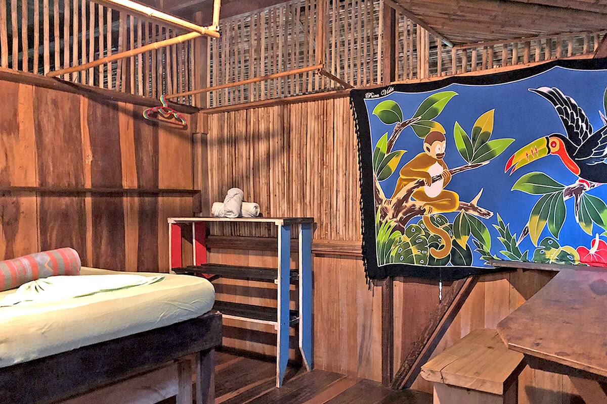 A room with a bed, a small table, and a colorful painting on the wall.