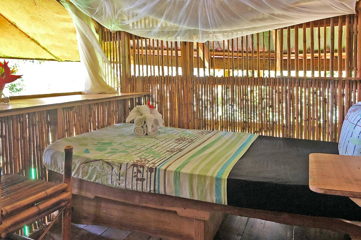 A room with a bed, a wooden table, and a mosquito net.