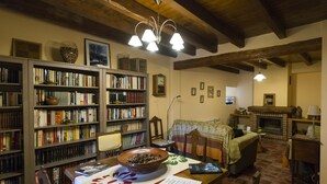 Una biblioteca acogedora con estanterías, chimenea y un comedor con mesa y sillas.