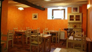 Un comedor con mesas y sillas de madera, un ventanal con vistas y un armario con puertas de cristal.