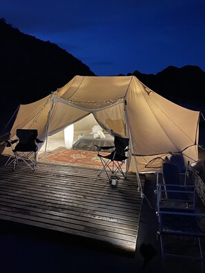 Ein Zelt mit einer Holterrasse, zwei Stühlen und einem kleinen Tisch.