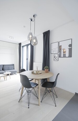 A modern dining area with a round table, two black chairs, and a pendant light.