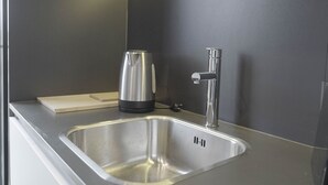 Una cocina moderna con un lavamanos de acero inoxidable, una tetera y un grifo.