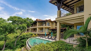 Un resort con piscina, varios balcones y abundante vegetación.