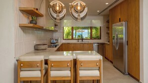 Una cocina moderna con una isla central, armarios de madera y un refrigerador de acero inoxidable.