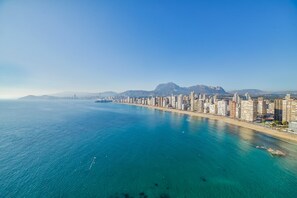 A coastal cityscape with a long beachfront, high-rise buildings, and mountains in the background.