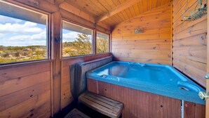 A wooden cabin with a hot tub, wooden walls, and a bench.