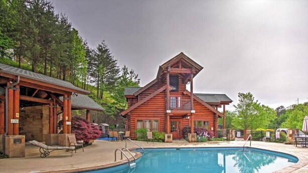 A wooden lodge with a swimming pool, lounge chairs, and a covered patio area.