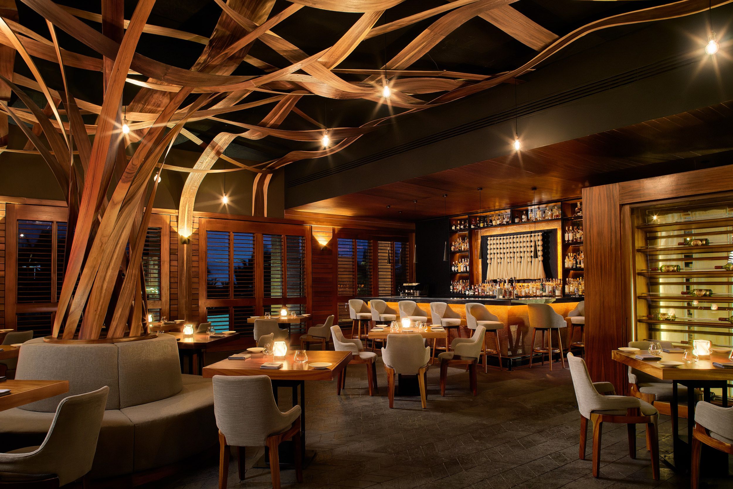A restaurant with wooden ceiling beams, tables, chairs, and a bar area.