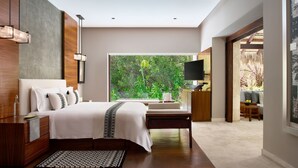 Un dormitorio moderno con una cama grande, mesitas de noche, un televisor y vistas a zonas verdes.
