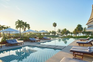 A pool area with lounge chairs and umbrellas, surrounded by palm trees. - Chablé Maroma (Playa del Carmen)