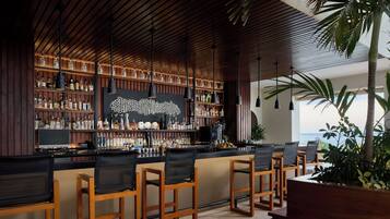 Zona de bar con sillas de madera, una barra y estantes llenos de botellas.